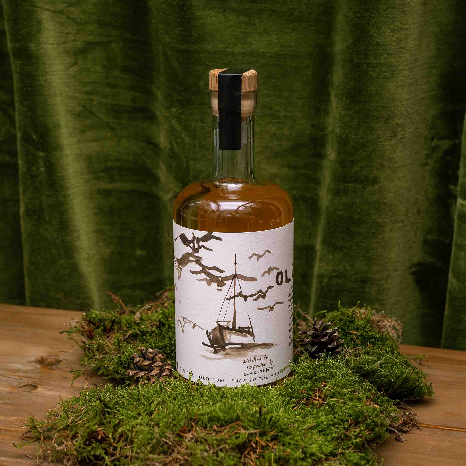 Ein Bild des Old Tom Gins. Dekoriert auf Moos mit Kiefernzapfen und olivfarbenem Hintergrund.
