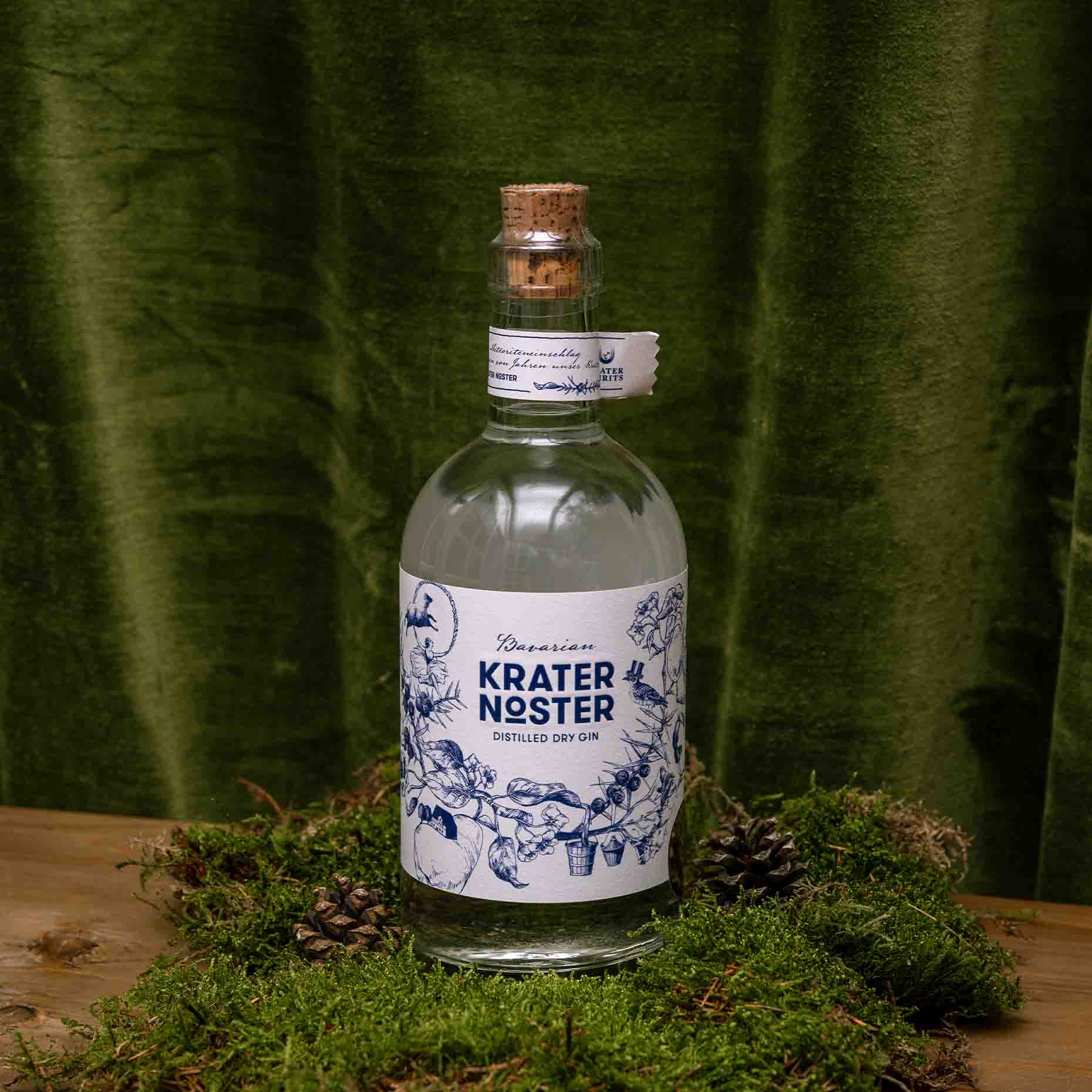 Ein Bild des Krater Noster Bavarian Distilled Dry Gin. Dekoriert auf Moos mit Kiefernzapfen und olivfarbenem Hintergrund.